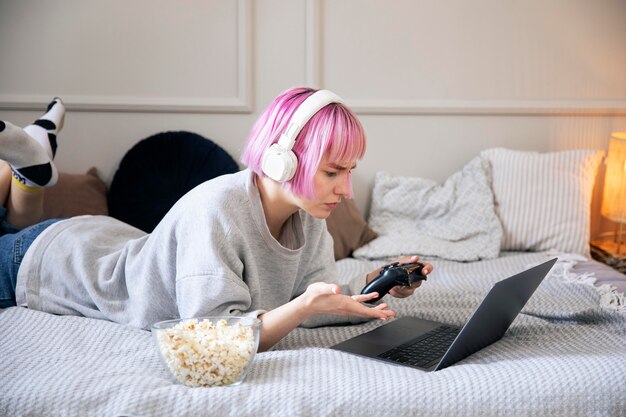 Young woman with pink hair playing with a joystick on the laptop
