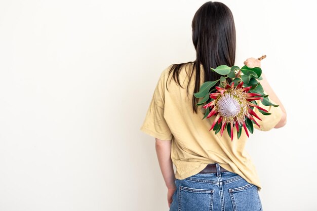 白い背景の上のプロテアの花を持つ若い女性