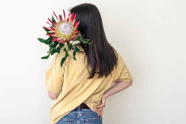 白い背景の上のプロテアの花を持つ若い女性