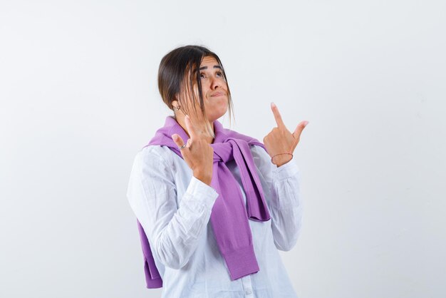 Young woman with puckering lips showing the top with fingers on white background