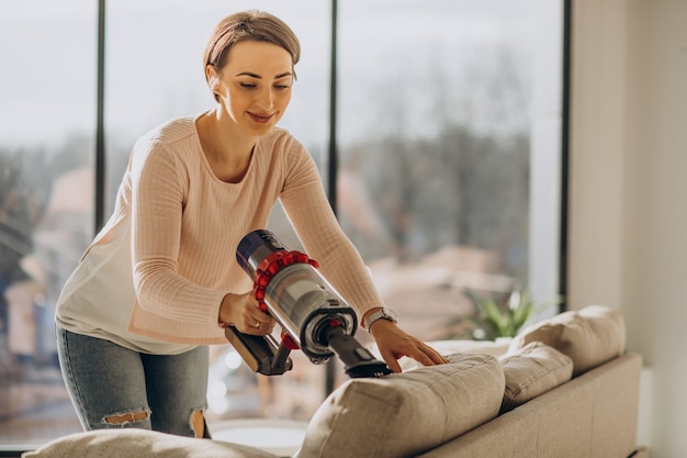 Free photo young woman with rechargeable vacuum cleaner cleaning at home