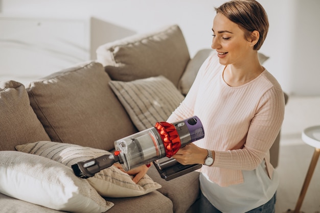 Young woman with rechargeable vacuum cleaner cleaning at home