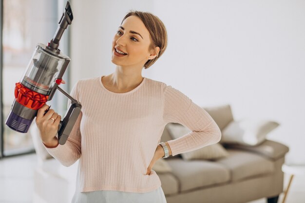 Young woman with rechargeable vacuum cleaner cleaning at home