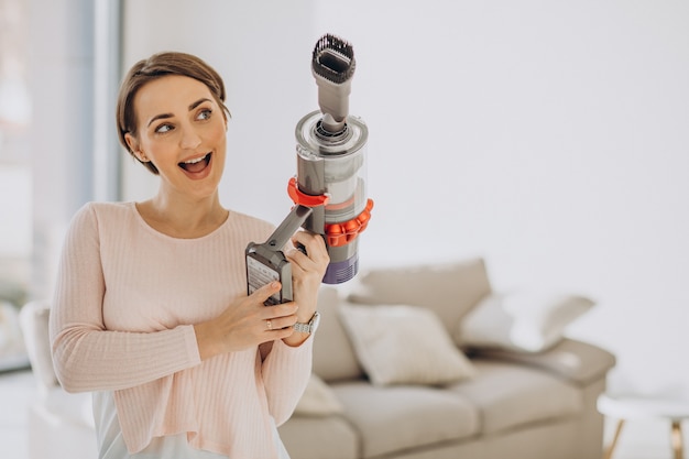 Young woman with rechargeable vacuum cleaner cleaning at home