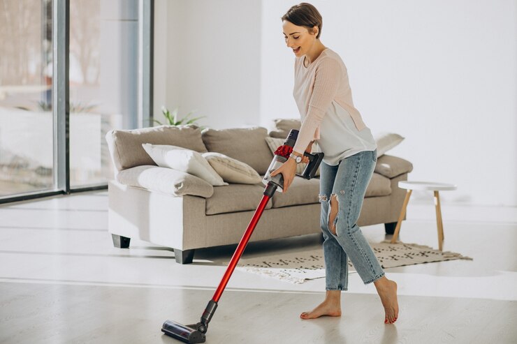 Free Photo young woman with rechargeable vacuum cleaner cleaning at home