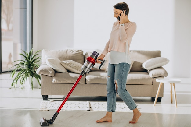 Free photo young woman with rechargeable vacuum cleaner cleaning at home