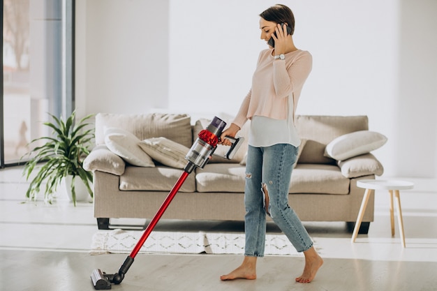 Foto gratuita giovane donna con aspirapolvere ricaricabile che pulisce a casa