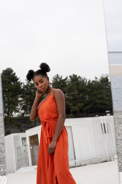 Young woman with red dress posing outdoors with mirror