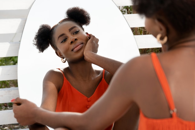 Young woman with red dress posing outside in mirror