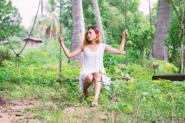 Young woman with a red flower swinging