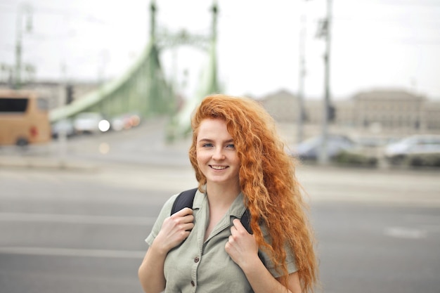 young woman with red hair and backpack in the street