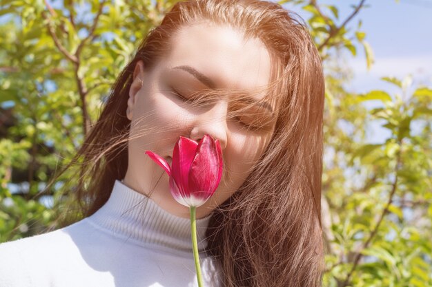 Молодая женщина с красным тюльпаном в саду весной