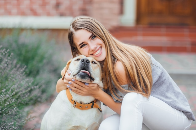 Young woman with retriever on walk in summer park