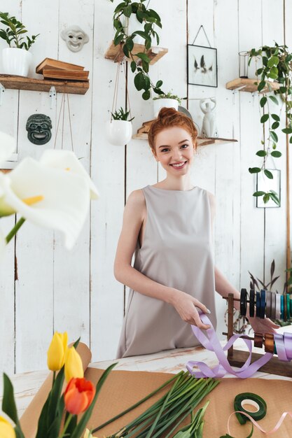 花と笑顔の間のリボンを持つ若い女性