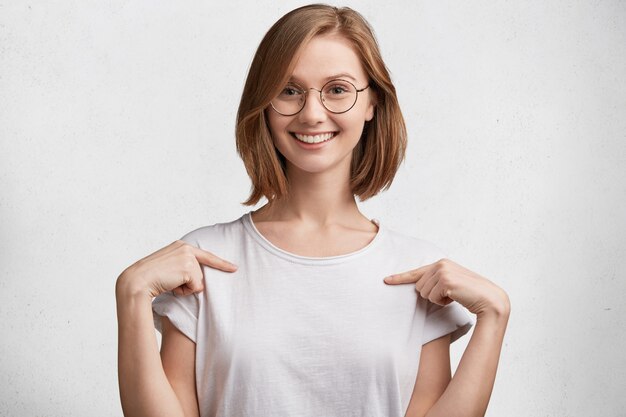 Молодая женщина в круглых очках и белой футболке