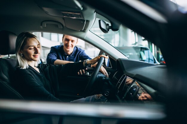 車のショールームでセールスマンを持つ若い女性