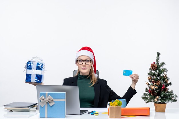 クリスマスツリーの近くのテーブルに座って 黄色で提示悲しいビジネスマンの正面図 無料の写真