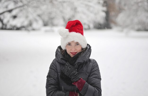 young woman with santa claus hat in a snowy park