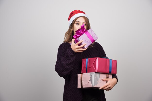 Young woman with Santa hat carrying gift boxes presents.