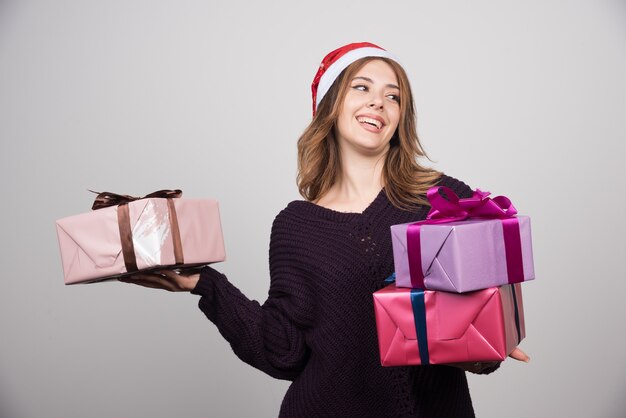 Young woman with Santa hat holding gift boxes presents.