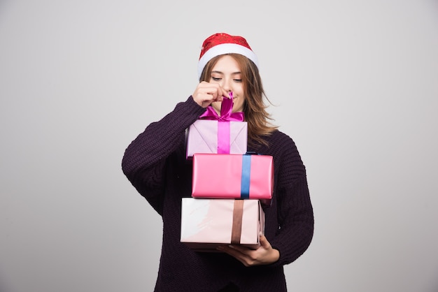 Young woman with Santa hat holding gift boxes presents.