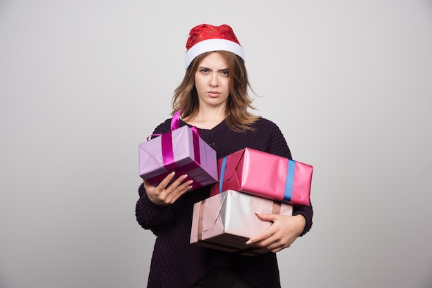 Young woman with Santa hat holding gift boxes presents.