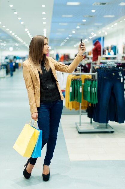 ショッピングバッグと携帯電話を持つ若い女性