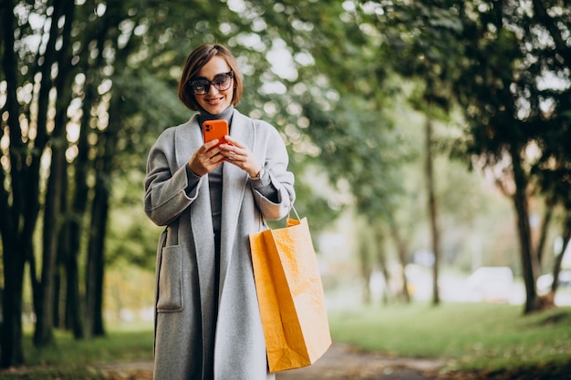 Free photo young woman with shopping bags in park