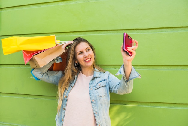 Selfieを取って買い物袋を持つ若い女