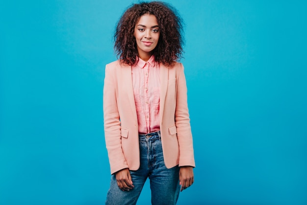 Young woman with short hair standing on blue wall