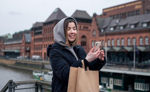 市内のスマートフォンと買い物袋を持つ若い女性
