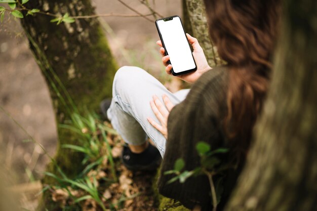 スマートフォンのテンプレートを自然の中で若い女性