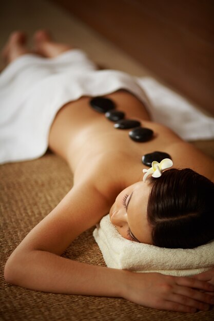 Young woman with spa stones on her back