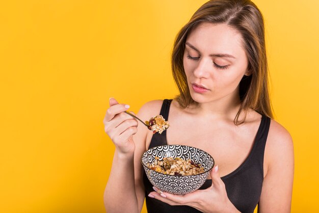 Young woman with spoon and bowl of flakes
