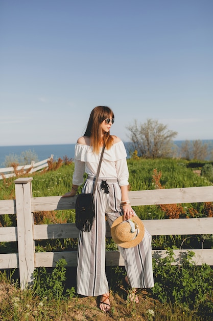 Young woman with straw hat by the fence in the countryside