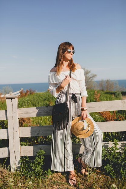 Young woman with straw hat by the fence in the countryside