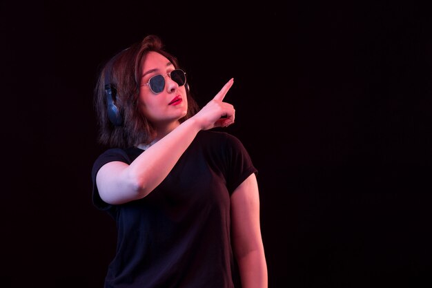 Young woman with sunglasses and black t-shirt pointing