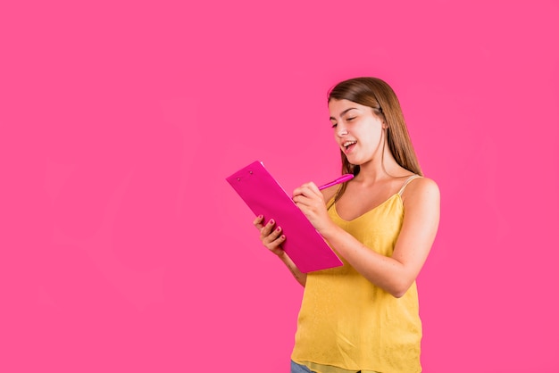 ピンクの背景の紙のためのタブレットを持つ若い女