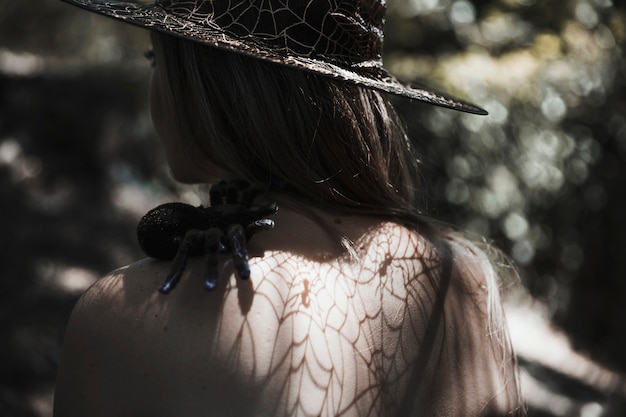 Free photo young woman with tarantula on shoulder in forest