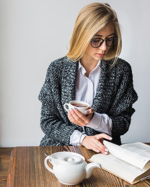 Young woman with tea reading book