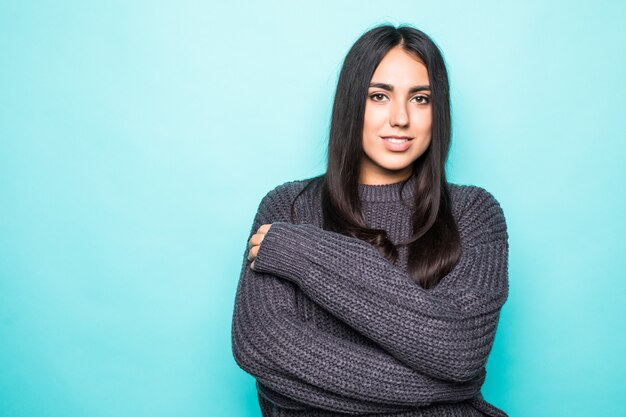 Young woman with a thoughtful friendly smile with her head tilted to the side and copy space isolated on blue