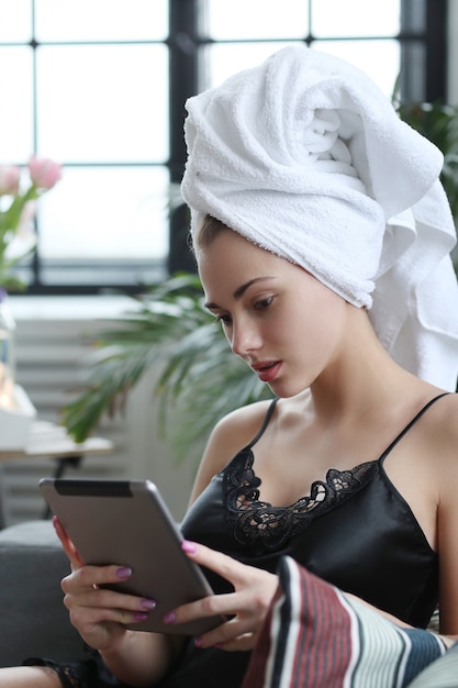 디지털 태블릿을 사용 하여 그녀의 머리에 수건으로 젊은 여자