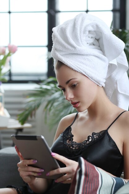 Young woman with towel on her head, using digital tablet