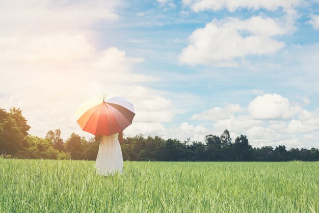 Young woman with umbrella in the meadow