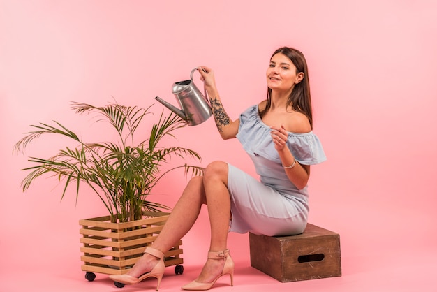 Free photo young woman with watering can near houseplant