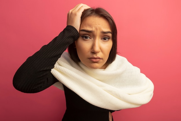 Foto gratuita giovane donna con sciarpa bianca confusa con la mano sulla sua testa