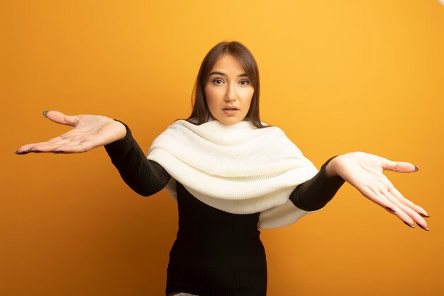 Young woman with white scarf confused with arms out 