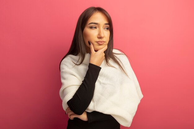 Young woman with white scarf looking aside puzzled 