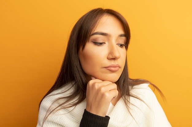 Young woman with white scarf looking aside with hand on chin thinking 