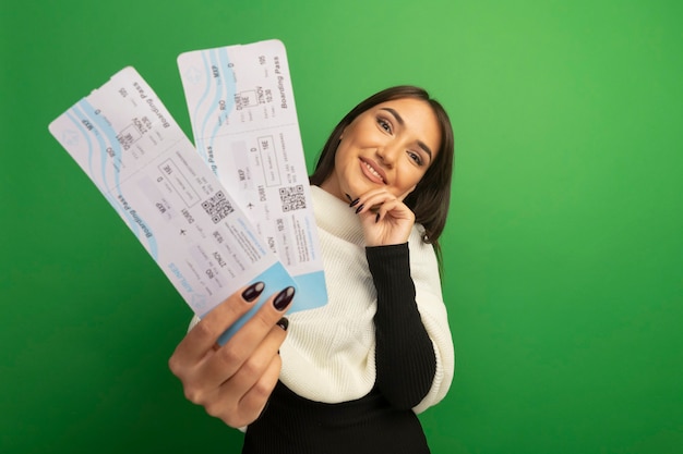 Foto gratuita giovane donna con sciarpa bianca che mostra i biglietti aerei con il sorriso sul viso felice e positivo